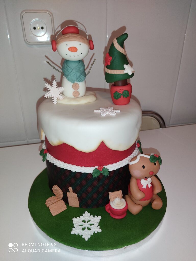 Tarta navideña decorada con figuras de Papá Noel y muñeco de nieve en fondant