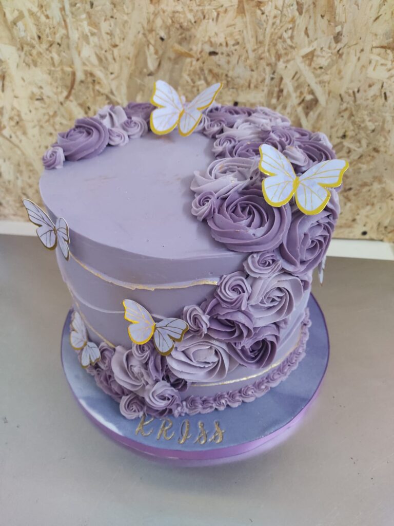 Tarta de ganache en color lila decorada con flores de chocolate y detalles elegantes