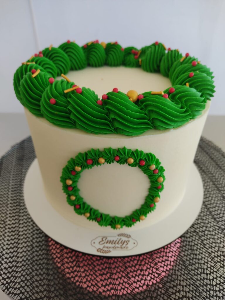 Tarta de ganache blanca decorada con una corona navideña verde y detalles festivos