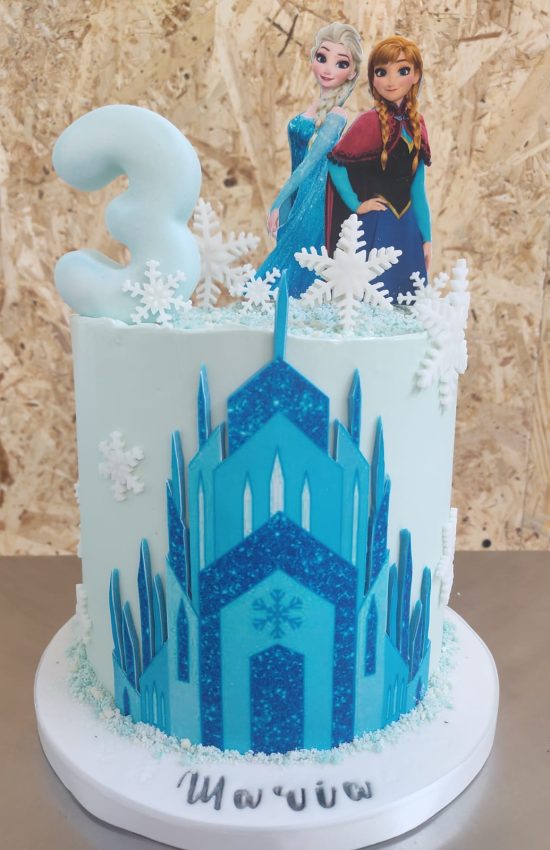 Tartas personalizadas en Madrid – diseño artesanal infantil de Frozen con figuras de Anna y Elsa, castillo de hielo en fondant y decoración azul y blanca