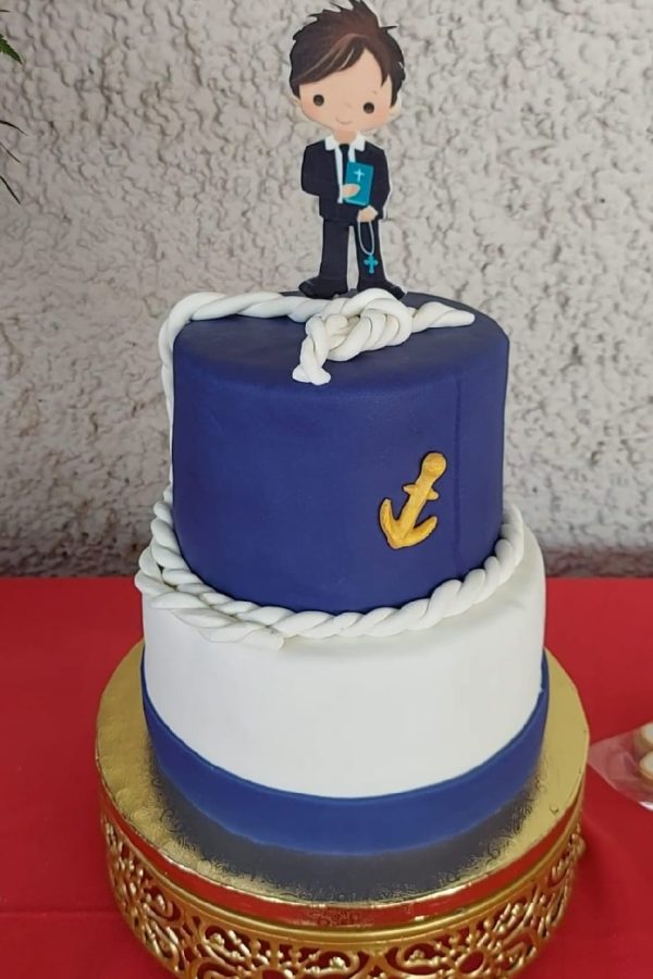 Tarta de primera comunión azul y blanca con figura de niño, decorada con crema artesanal dulce.