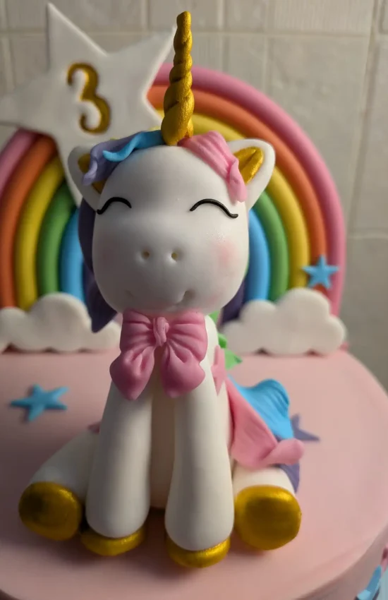 Figura de unicornio y arcoíris en fondant sobre tarta infantil personalizada artesanal
